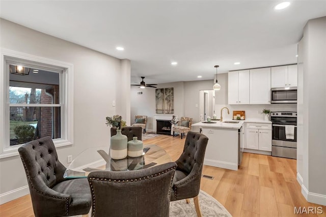 83 Chafford Woods, Saint Louis, MO 63144 - dining area featuring light wood-type flooring, ceiling fan, recessed lighting, and a fireplace