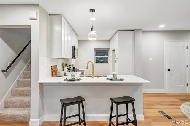 83 Chafford Woods, Saint Louis, MO 63144 - kitchen with a peninsula, white cabinets, light countertops, stainless steel microwave, and a breakfast bar