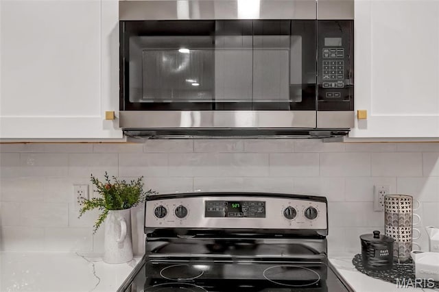 83 Chafford Woods, Saint Louis, MO 63144 - kitchen view of stainless steel electric stove, decorative backsplash, light stone counters, and white cabinets