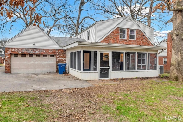 83 Chafford Woods, Saint Louis, MO 63144 - back of house with a sunroom, brick siding, a garage, and driveway