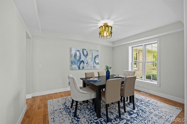 dining space with a chandelier, baseboards, and wood finished floors