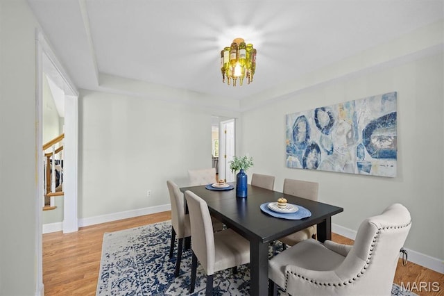 dining room with light wood-type flooring, baseboards, a chandelier, and stairway