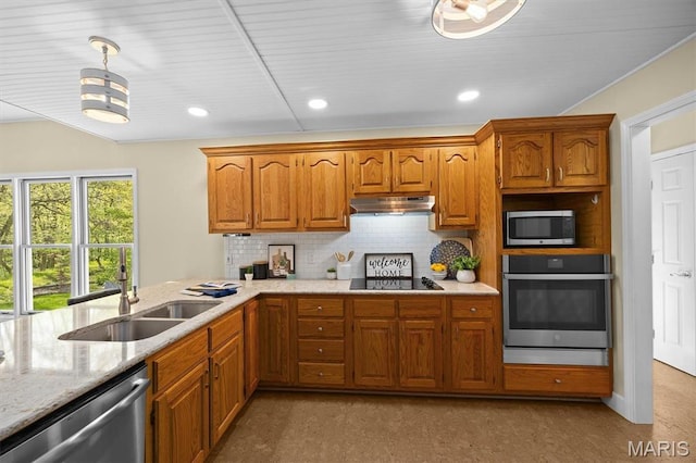 kitchen featuring appliances with stainless steel finishes, under cabinet range hood, a sink, tasteful backsplash, and brown cabinetry