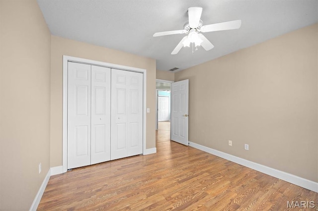 unfurnished bedroom featuring baseboards, a closet, light wood-type flooring, and a ceiling fan