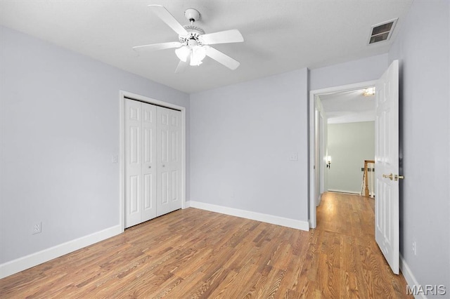 unfurnished bedroom with light wood finished floors, a closet, baseboards, and ceiling fan