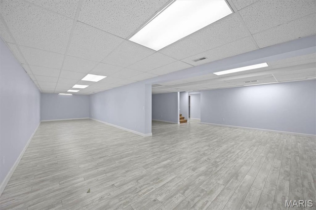 finished below grade area with a paneled ceiling, wood finished floors, and baseboards