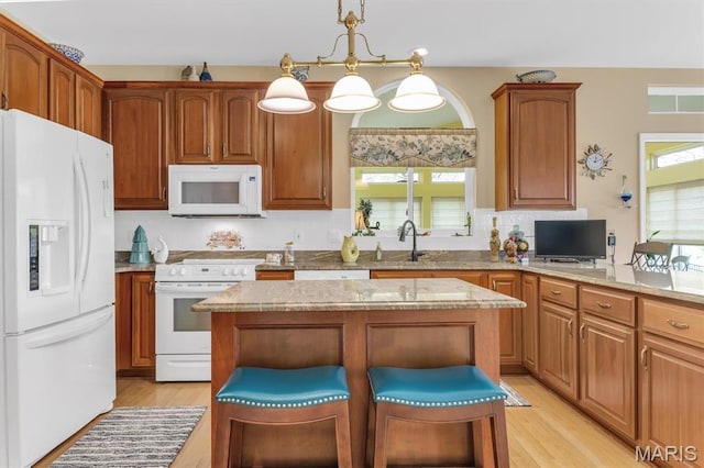 13463 Keller Ridge Cv, Saint Louis, MO 63128 - kitchen featuring white appliances, light wood finished floors, a center island, a breakfast bar, and light stone countertops