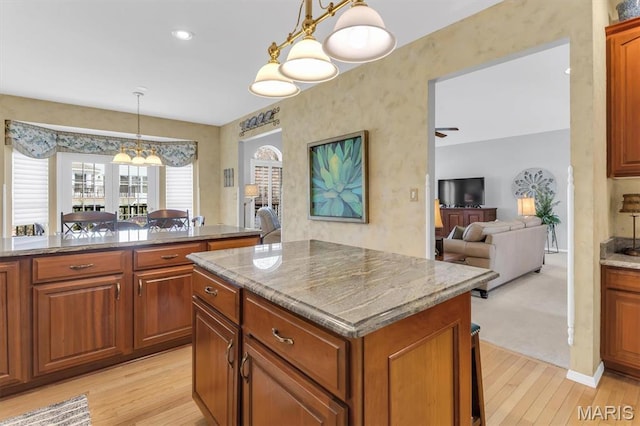13463 Keller Ridge Cv, Saint Louis, MO 63128 - kitchen featuring a kitchen island, light wood-style flooring, brown cabinets, and hanging light fixtures