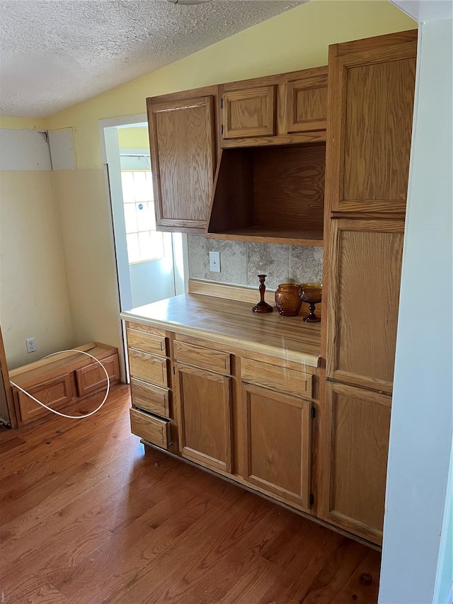 2717 Creon Ct, De Soto, MO 63020 - kitchen with dark wood-style flooring, light countertops, a textured ceiling, brown cabinets, and backsplash