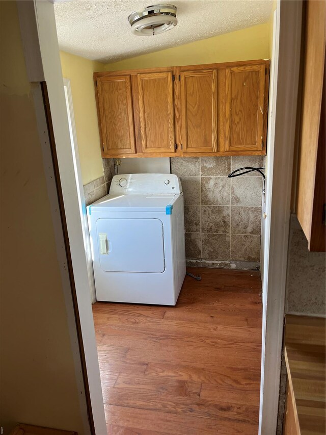 2717 Creon Ct, De Soto, MO 63020 - clothes washing area with washer / clothes dryer, cabinet space, light wood finished floors, and a textured ceiling