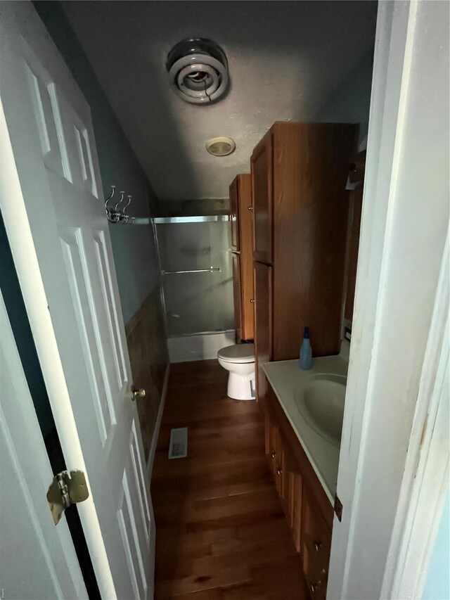 2717 Creon Ct, De Soto, MO 63020 - full bath featuring wood finished floors, toilet, vanity, and shower / bath combination with glass door