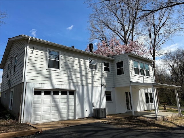 1300 Hudson Rd, Saint Louis, MO 63135 - back of house with a garage, central air condition unit, and asphalt driveway