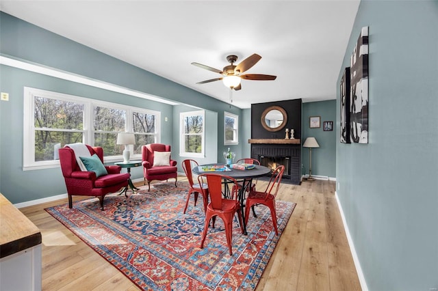 1300 Hudson Rd, Saint Louis, MO 63135 - dining space featuring a brick fireplace, baseboards, light wood-style flooring, and ceiling fan
