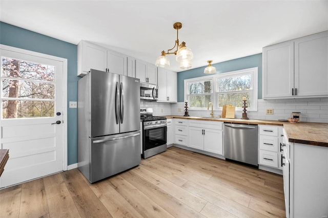 1300 Hudson Rd, Saint Louis, MO 63135 - kitchen featuring stainless steel appliances, butcher block counters, a sink, tasteful backsplash, and a chandelier