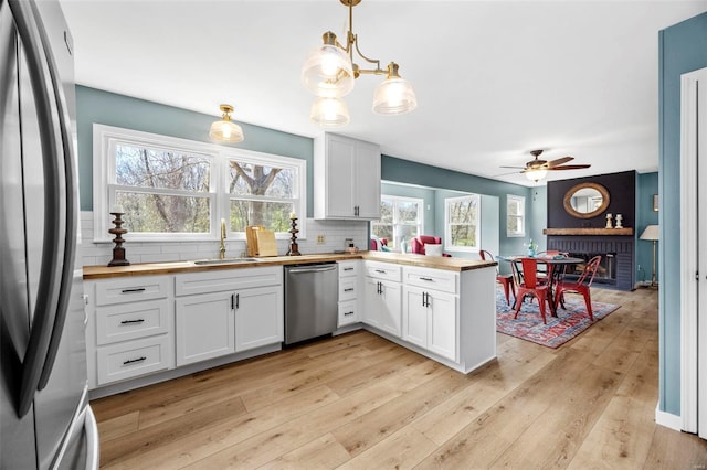 1300 Hudson Rd, Saint Louis, MO 63135 - kitchen featuring appliances with stainless steel finishes, a sink, butcher block counters, a peninsula, and tasteful backsplash