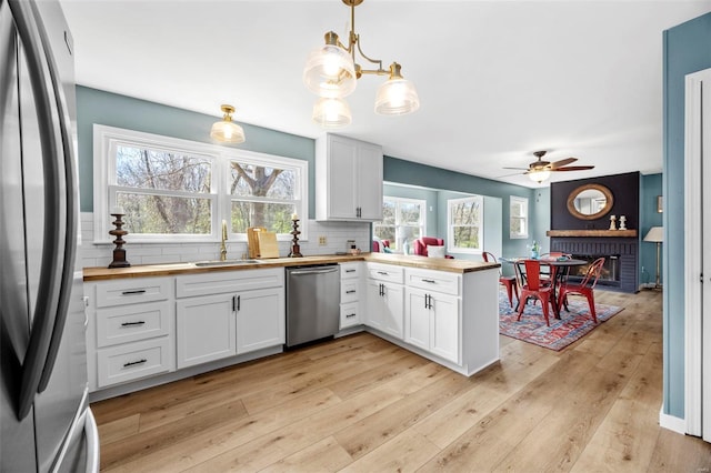 1300 Hudson Rd, Saint Louis, MO 63135 - kitchen featuring stainless steel appliances, a sink, butcher block counters, a peninsula, and tasteful backsplash