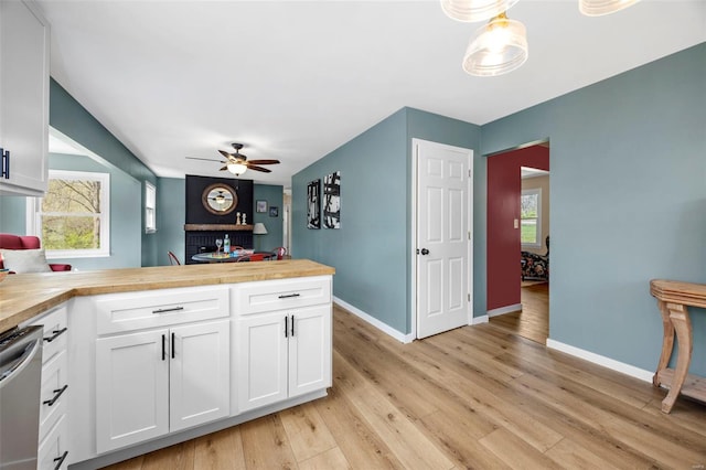 1300 Hudson Rd, Saint Louis, MO 63135 - kitchen featuring a ceiling fan, a peninsula, white cabinetry, baseboards, and light wood finished floors