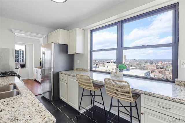 4466 W Pine Blvd Unit 23C, Saint Louis, MO 63108 - kitchen featuring freestanding refrigerator, white cabinetry, stove, dark tile patterned floors, and light stone counters