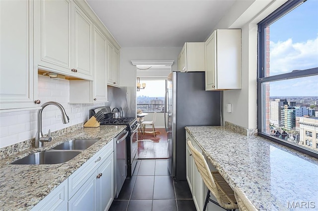 4466 W Pine Blvd Unit 23C, Saint Louis, MO 63108 - kitchen featuring a sink, white cabinets, light stone countertops, backsplash, and appliances with stainless steel finishes