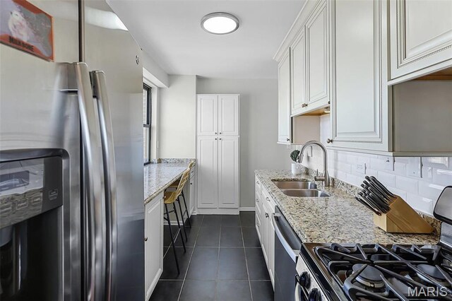 4466 W Pine Blvd Unit 23C, Saint Louis, MO 63108 - kitchen with appliances with stainless steel finishes, a sink, dark tile patterned flooring, white cabinetry, and light stone counters