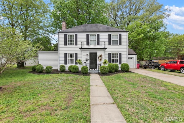 view of front of house featuring a balcony, a chimney, driveway, a front lawn, and a garage