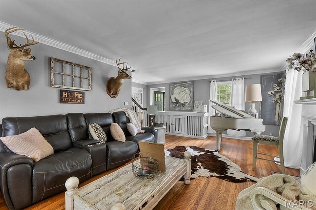 living area with crown molding, wood finished floors, stairway, and a fireplace
