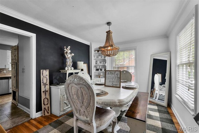 dining room with a chandelier, crown molding, wood finished floors, and baseboards