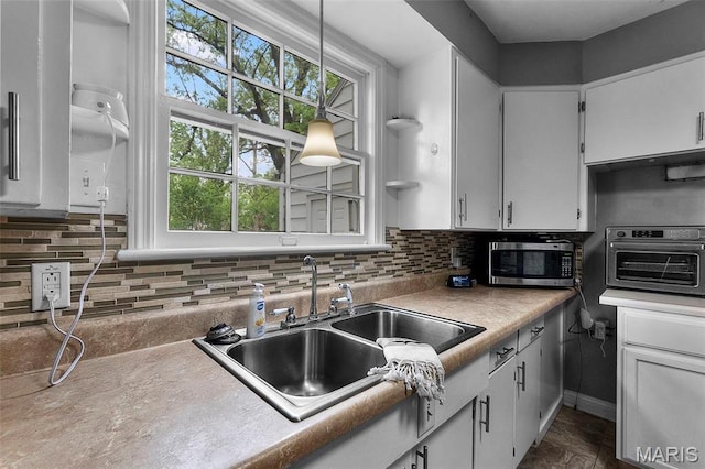 kitchen featuring stainless steel microwave, a sink, plenty of natural light, and white cabinets