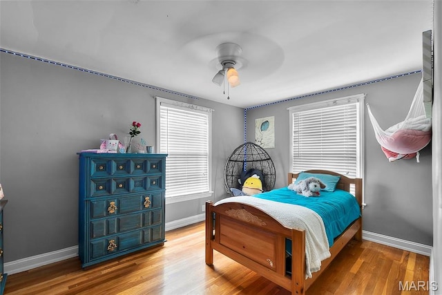 bedroom featuring baseboards, wood finished floors, and a ceiling fan