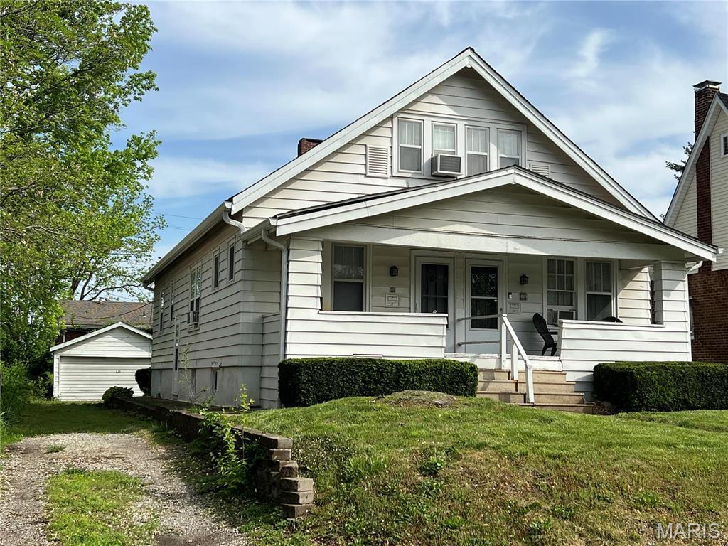 31 S 88th St, Belleville, IL 62223 - bungalow featuring covered porch, a front lawn, a chimney, a garage, and cooling unit