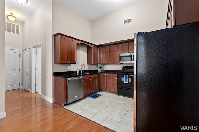 1515 Lafayette Ave Unit 316, Saint Louis, MO 63104 - kitchen featuring appliances with stainless steel finishes, a high ceiling, light wood-style flooring, dark countertops, and a sink