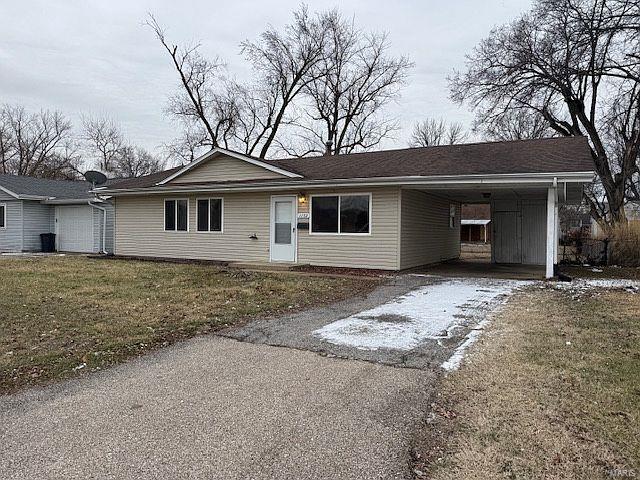 single story home featuring driveway, an attached carport, and a front lawn