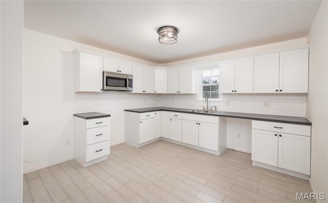 12000 State Rte E, Rolla, MO 65401 - kitchen featuring stainless steel microwave, backsplash, dark countertops, and white cabinets
