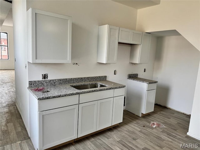 1519 Mallinckrodt St, Saint Louis, MO 63107 - kitchen with a sink, light wood-style flooring, stone countertops, and white cabinetry