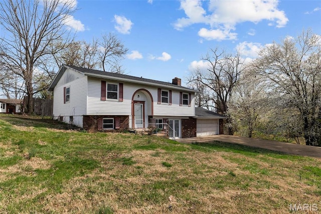 953 E 1st St, Washington, MO 63090 - split foyer home with a chimney, concrete driveway, a front lawn, and an attached garage
