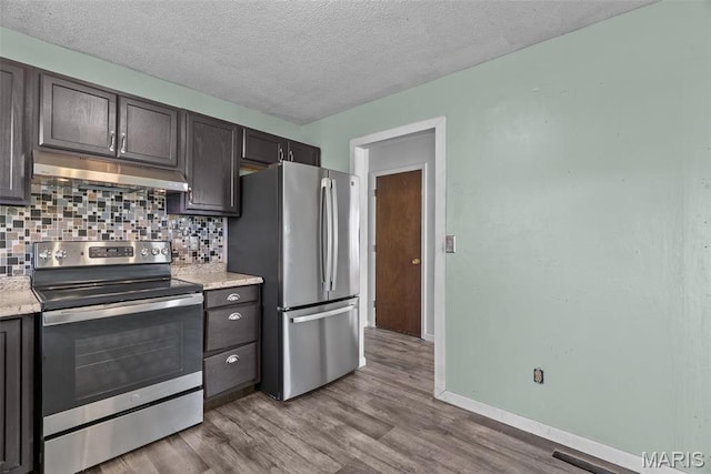 953 E 1st St, Washington, MO 63090 - kitchen featuring appliances with stainless steel finishes, under cabinet range hood, backsplash, wood finished floors, and a textured ceiling