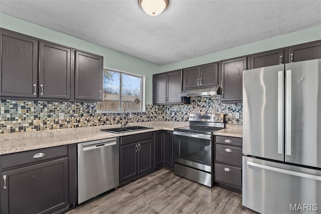 953 E 1st St, Washington, MO 63090 - kitchen with appliances with stainless steel finishes, a sink, under cabinet range hood, light countertops, and a textured ceiling