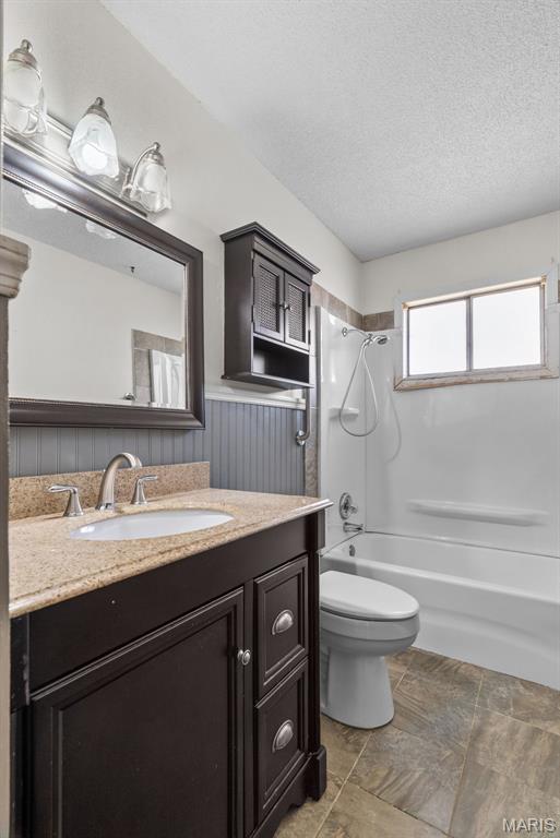 953 E 1st St, Washington, MO 63090 - bathroom with  shower combination, toilet, vanity, a wainscoted wall, and a textured ceiling