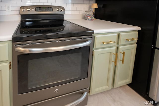 749 Sugar Glen Dr Unit 8, Saint Peters, MO 63376 - kitchen featuring stainless steel electric range oven, tasteful backsplash, light countertops, and green cabinets