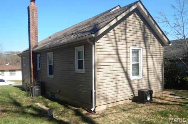7122 Dawson Pl, Saint Louis, MO 63136 - view of side of property with central air condition unit, a chimney, and a lawn