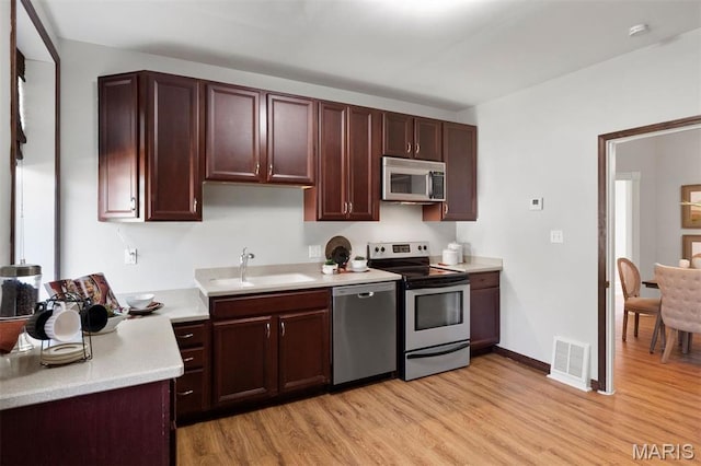 4525 Oakland Ave, Saint Louis, MO 63110 - kitchen featuring appliances with stainless steel finishes, light wood-style floors, light countertops, a sink, and baseboards