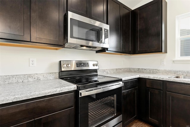 16787 River Stone Dr, Florissant, MO 63031 - kitchen with appliances with stainless steel finishes, light countertops, dark brown cabinets, and wood finished floors