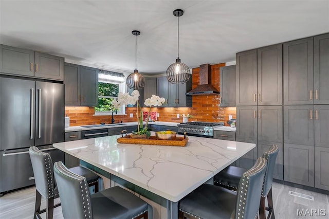 406 Meyer Ave, Saint Louis, MO 63122 - kitchen featuring high end fridge, wall chimney exhaust hood, light stone counters, and a kitchen breakfast bar