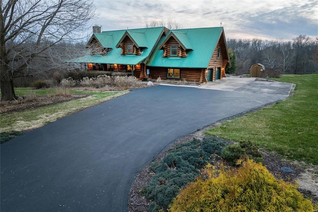 log home with log exterior, a chimney, asphalt driveway, and a porch