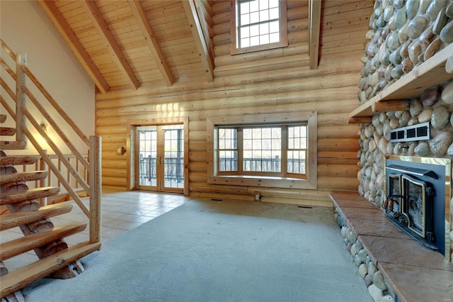 unfurnished living room featuring a towering ceiling, french doors, rustic walls, wooden ceiling, and carpet