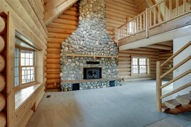 unfurnished living room with log walls, stairway, carpet, a stone fireplace, and a towering ceiling