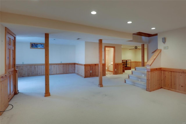 finished below grade area featuring a wainscoted wall, wooden walls, carpet flooring, recessed lighting, and stairway