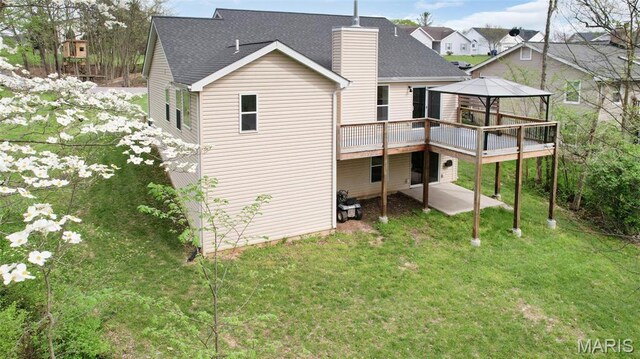 rear view of house featuring a gazebo, a wooden deck, a chimney, a yard, and a patio area