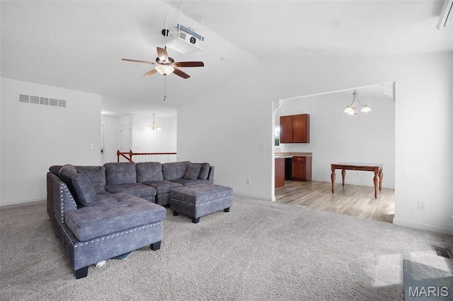 living room with a chandelier, light colored carpet, lofted ceiling, a ceiling fan, and baseboards