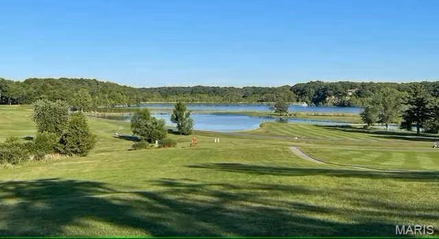 view of home's community with view of golf course, a water view, and a yard